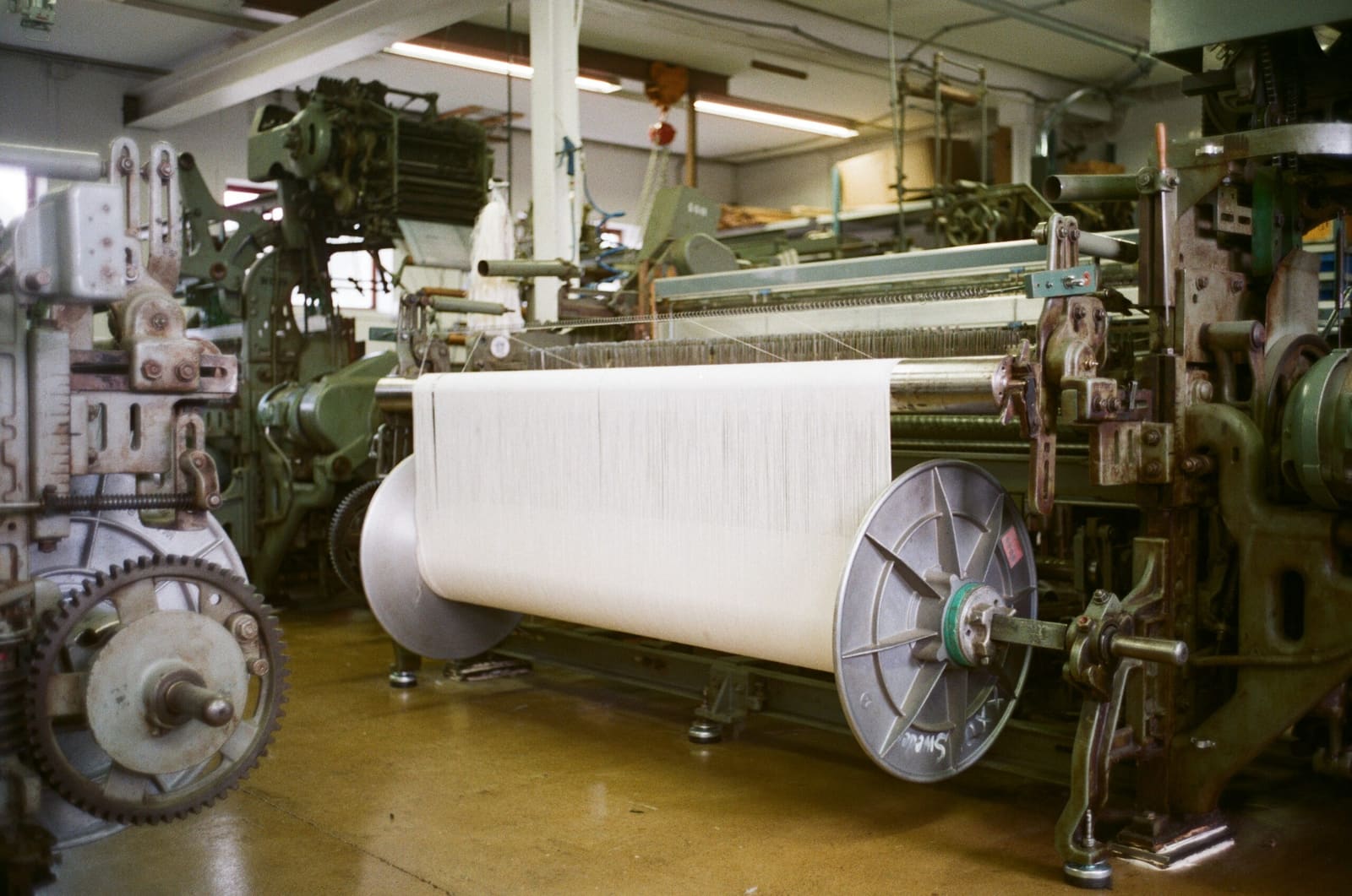 An industrial loom running a wide roll of white fibre