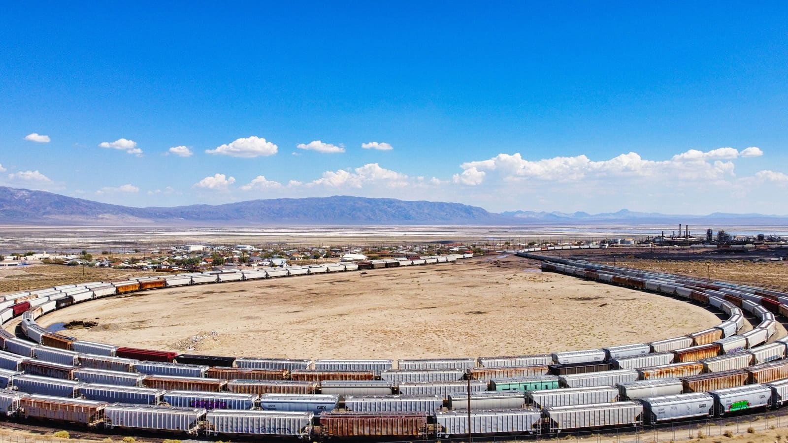 Hundreds of freight hoppers curving through a rail yard in an open desert basin